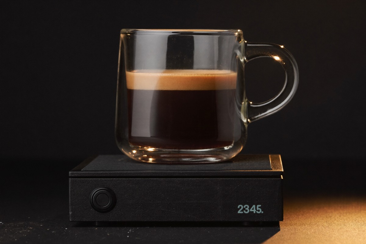 A double espresso pulling into a glass, tiger-striped crema forming.