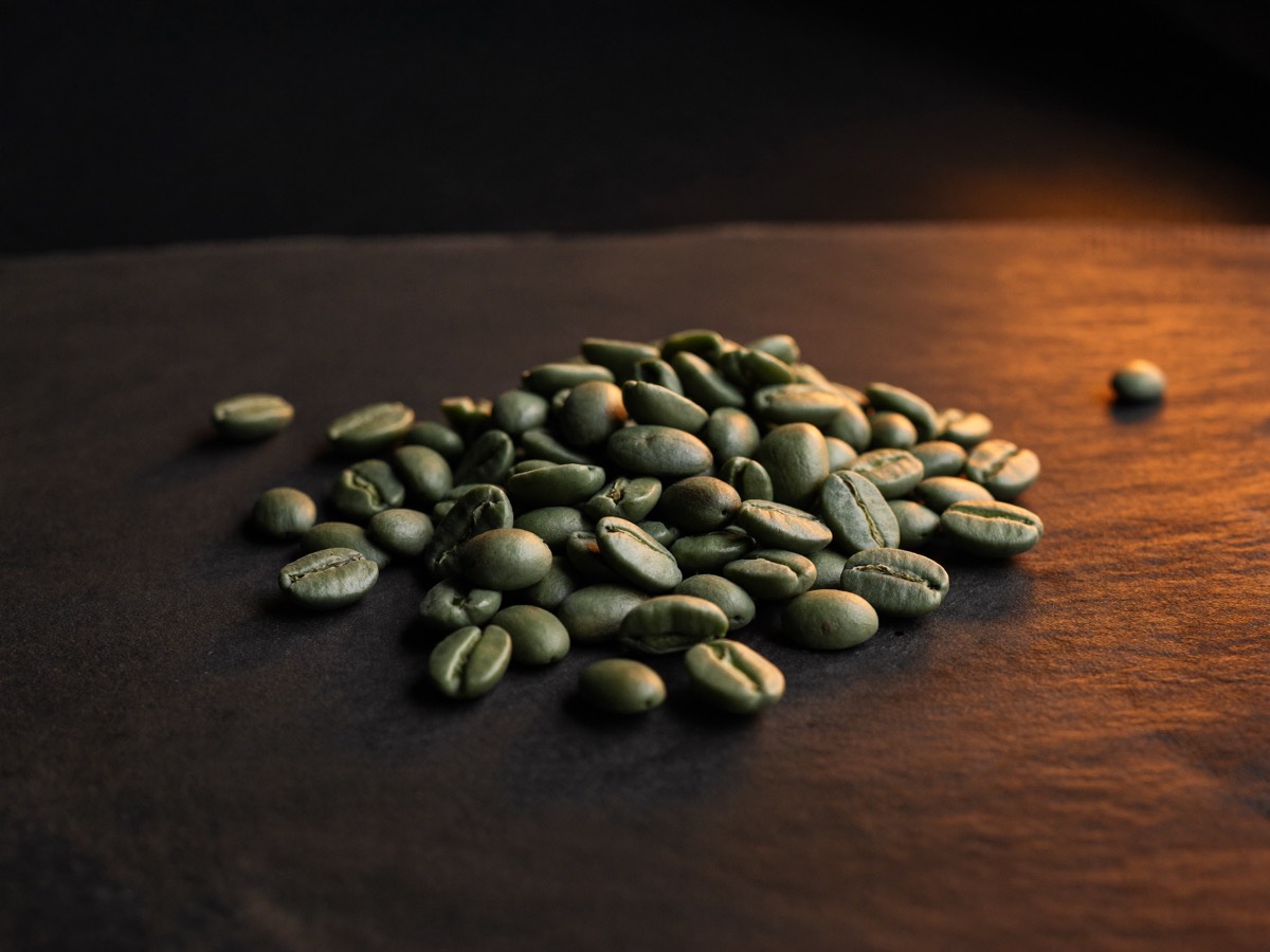 Green and roasted coffee beans sorted on a steel tray.