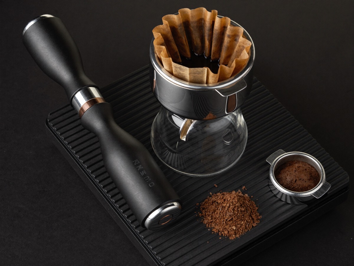 A leveled dose of coffee in a portafilter on a scale reading 18.0 grams.