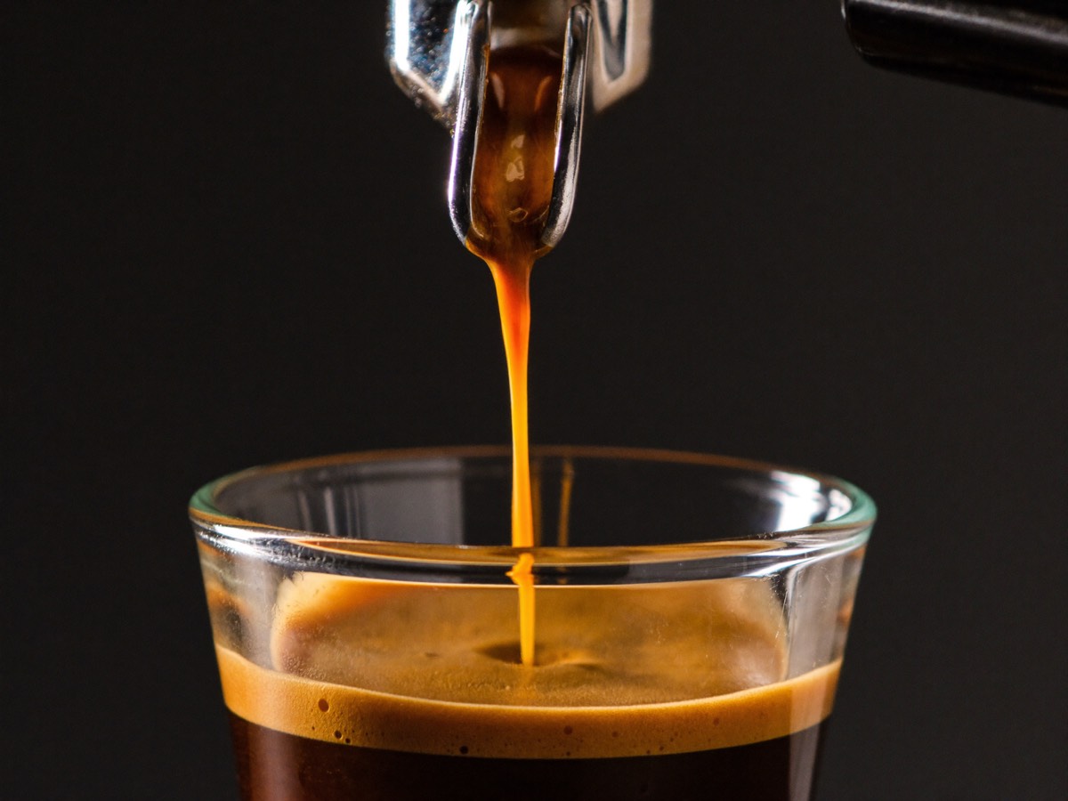 Espresso extracting from a bottomless portafilter in a steady stream.