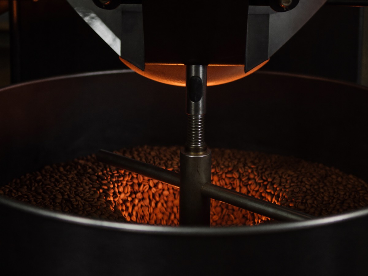 Beans tumbling in the glass door of a drum roaster, mid-roast.